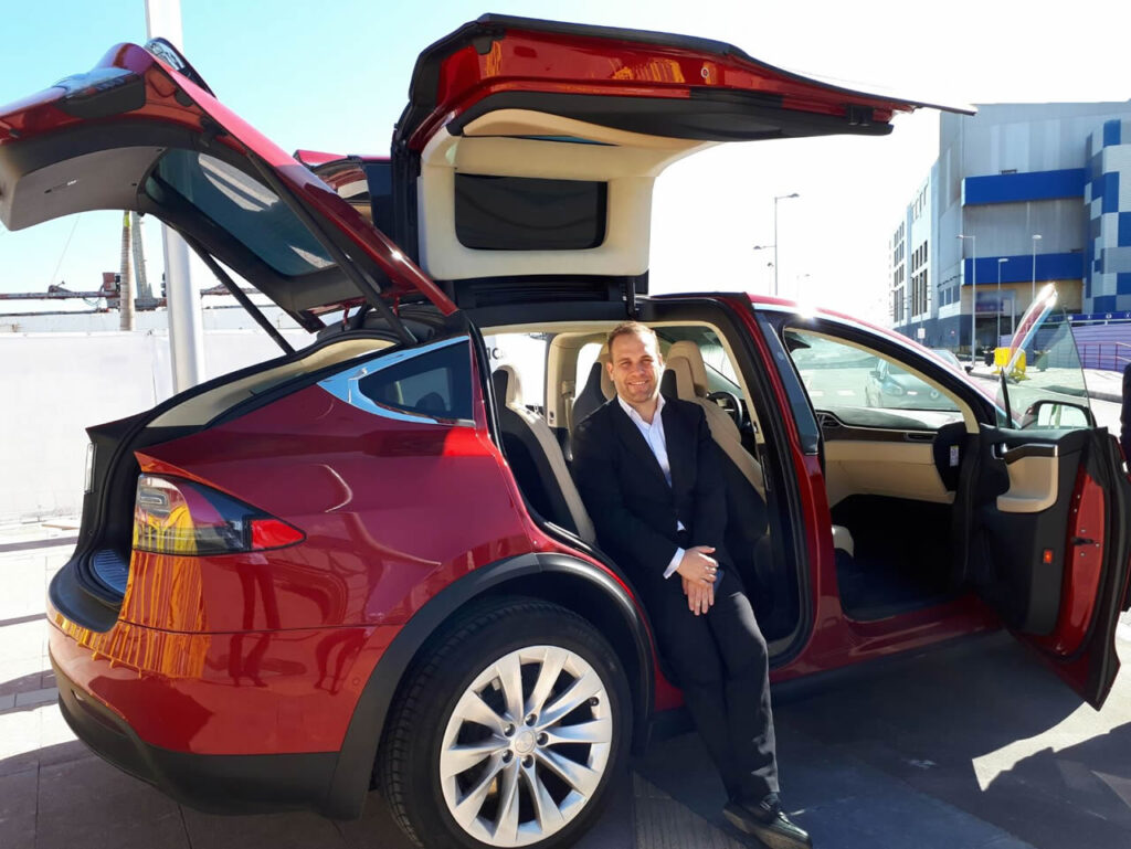 Angel Treviño posa dentro un vehículo eléctrico. Es coche eléctrico es un Tesla, y es el primero que vino a Canarias.